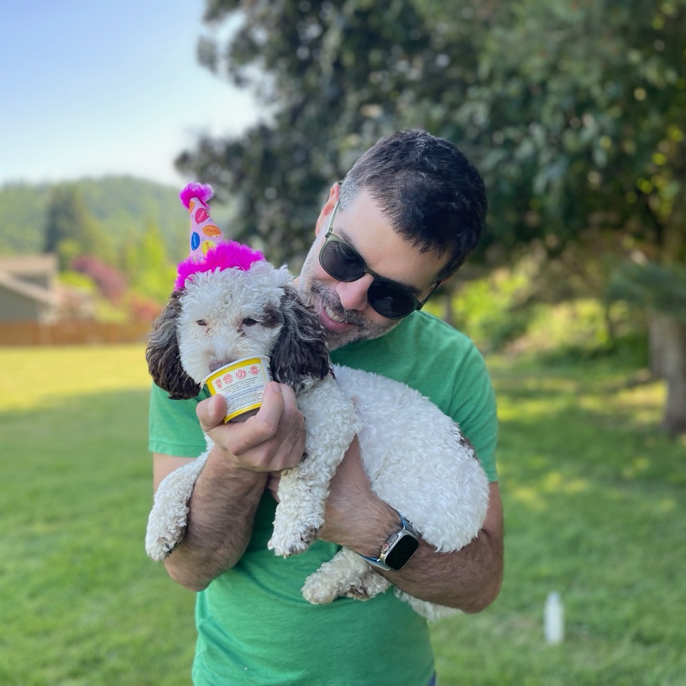 Matthew Westerbeck holding his dog, who is wearing a party hat